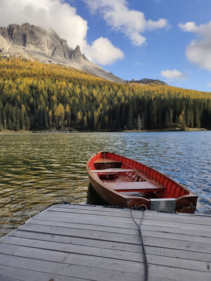 pexels-photo-3146773 Tranquil scene of a wooden boat on a mountain lake dock with scenic forest and mountain backdrop.